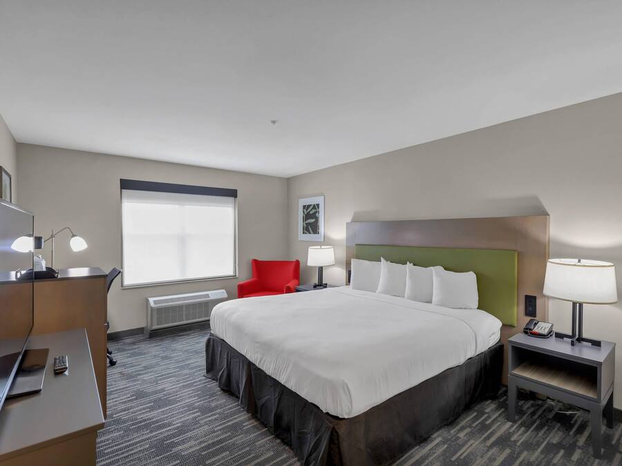 Ein Hotelzimmer mit Bett, Schreibtisch, Stuhl, Nachttischlampen und einem Fenster.