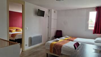 Une chambre d’hôtel avec deux lits, un téléviseur fixé au mur, une fenêtre avec des rideaux rouges et un radiateur.