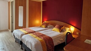 Un lit double avec une tête de lit en bois, une table de chevet et un mur d’accent rouge.