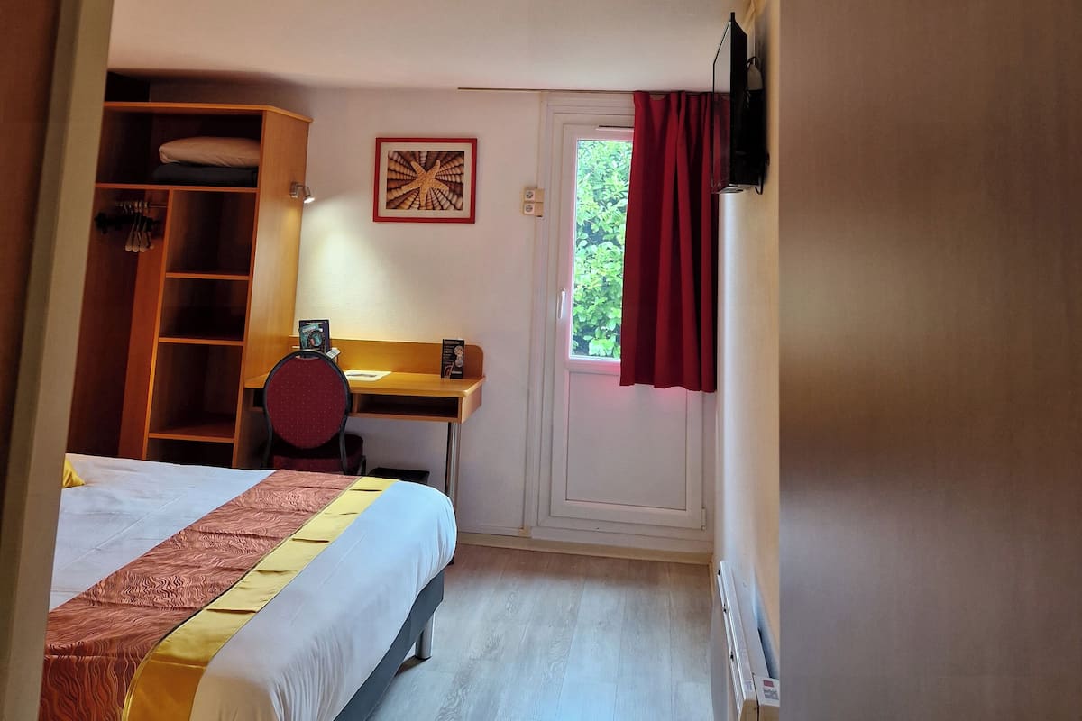 Un dormitorio con cama, escritorio, armario y puerta con ventana.