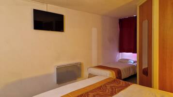 Quarto de hotel com duas camas, televisão fixada na parede e porta de madeira.
