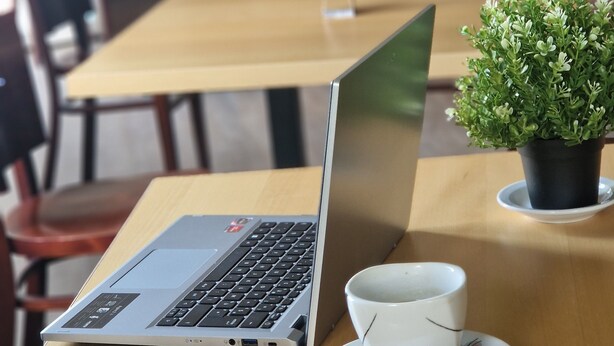 Un café avec un ordinateur portable, des pâtisseries et une plante en pot sur une table.