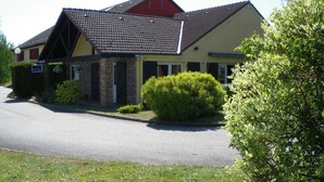 Un bâtiment à deux étages, avec un toit rouge et une enseigne indiquant qu’il s’agit d’un hôtel.