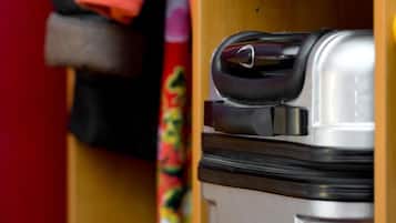 A wooden shelf with a red jacket, a black jacket, and a colorful scarf.