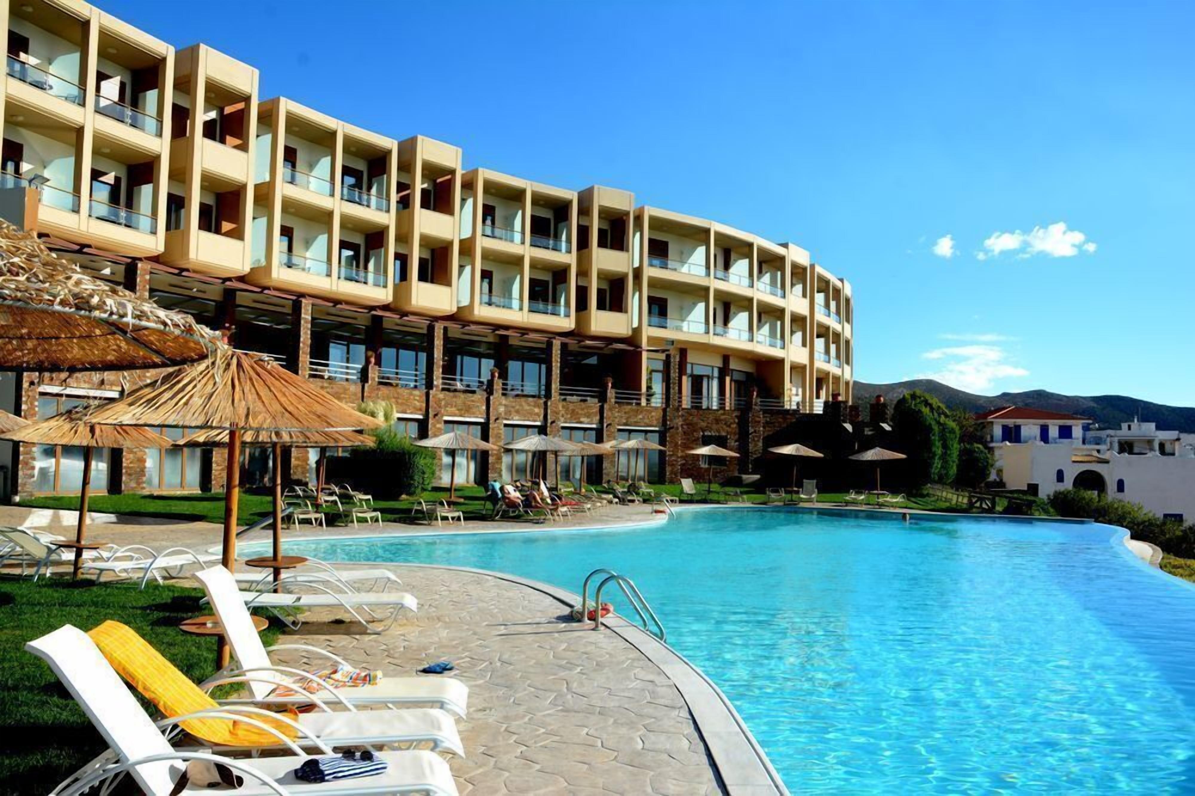 Un hotel con piscina, sillas de descanso y sombrillas.