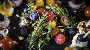 A variety of fruits and vegetables, including tomatoes, blueberries, and raspberries, arranged on a dark surface.