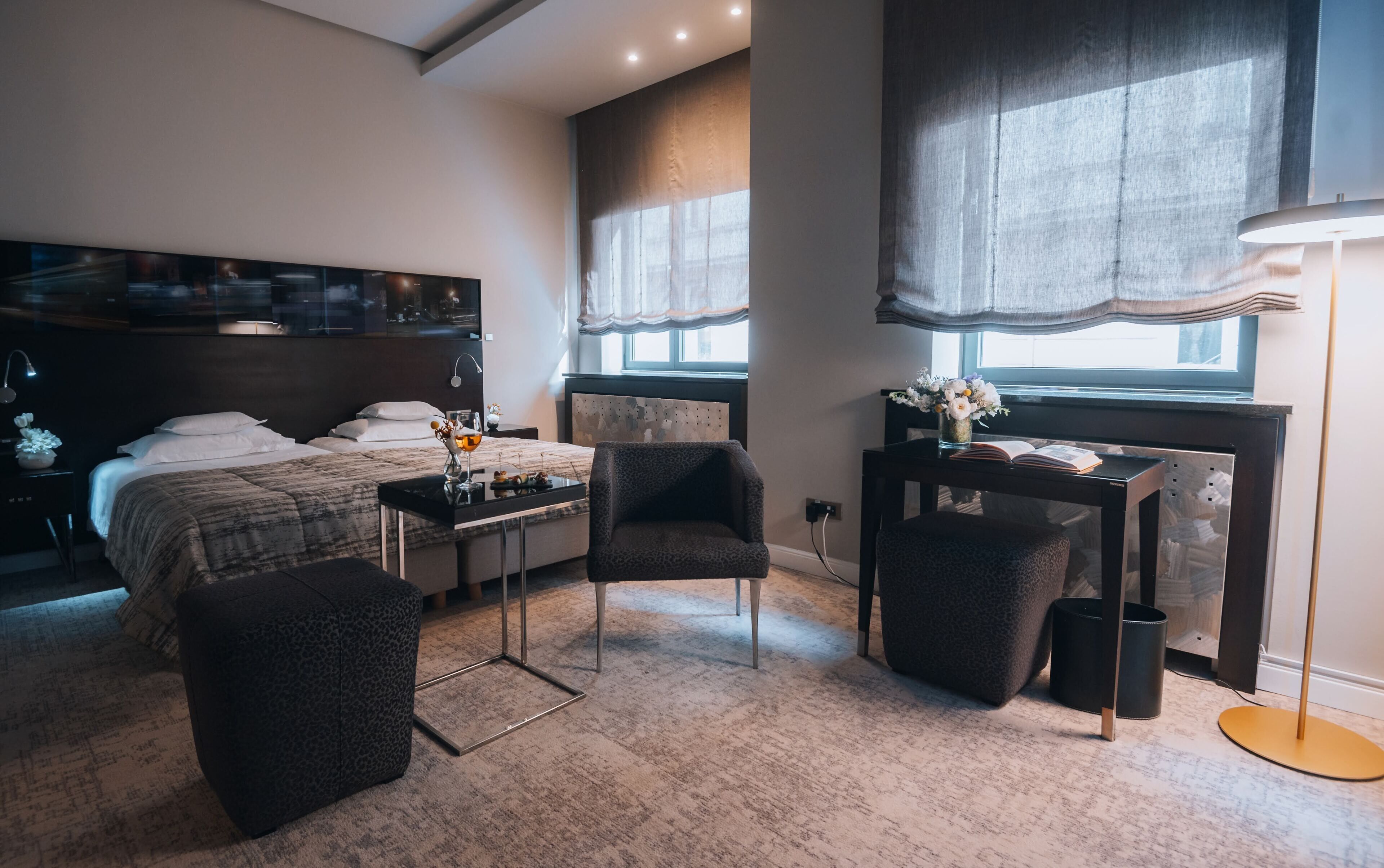 A modern bedroom with a bed, a desk, a chair, and a large window.