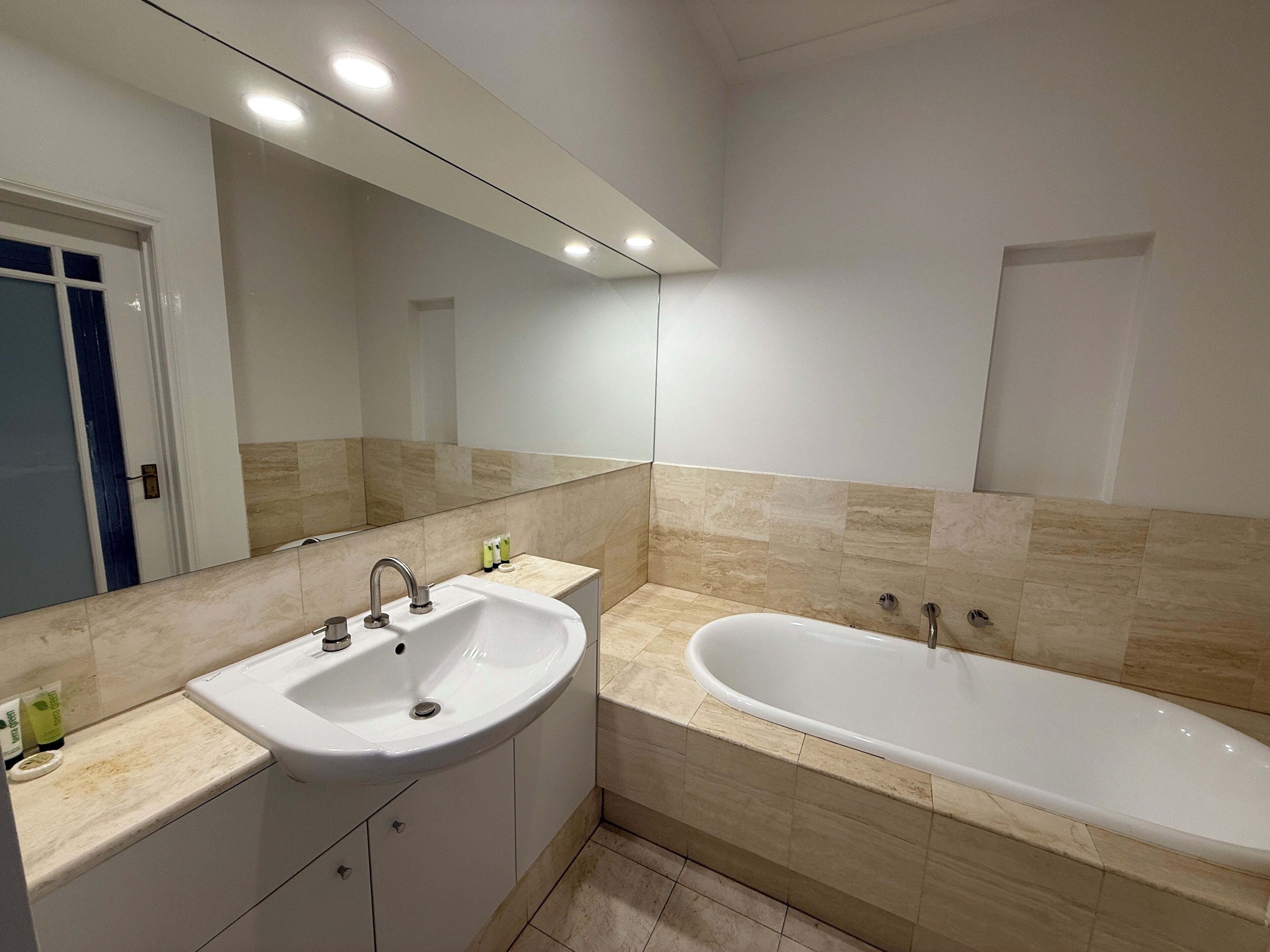 Un baño moderno con lavabo, espejo y bañera.