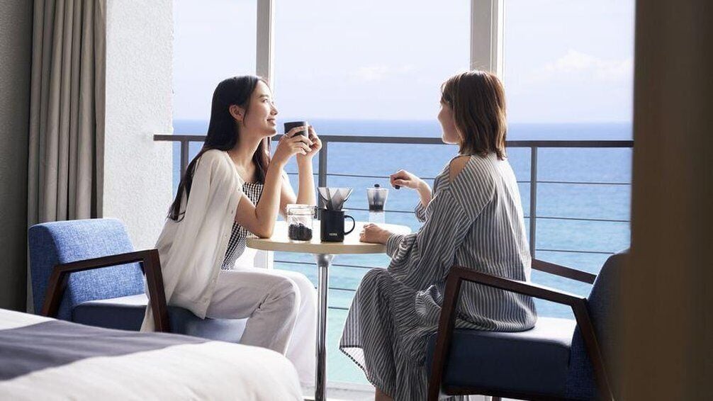 Zwei Personen sitzen an einem Tisch mit Blick auf das Meer.