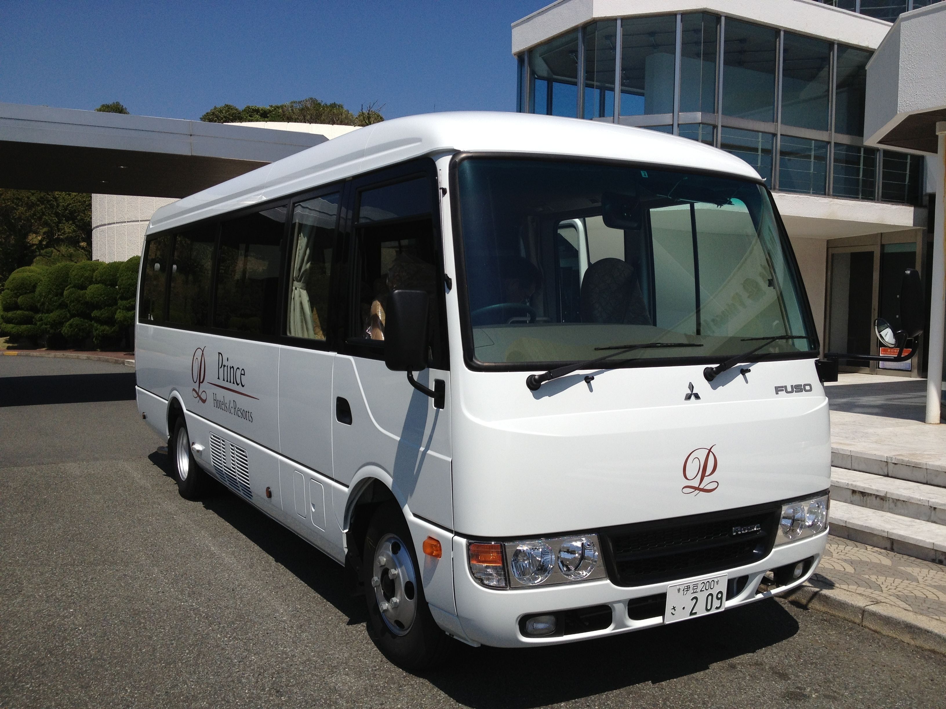 A white bus with "Prince Hotels & Resorts" branding parked in front of a modern building.