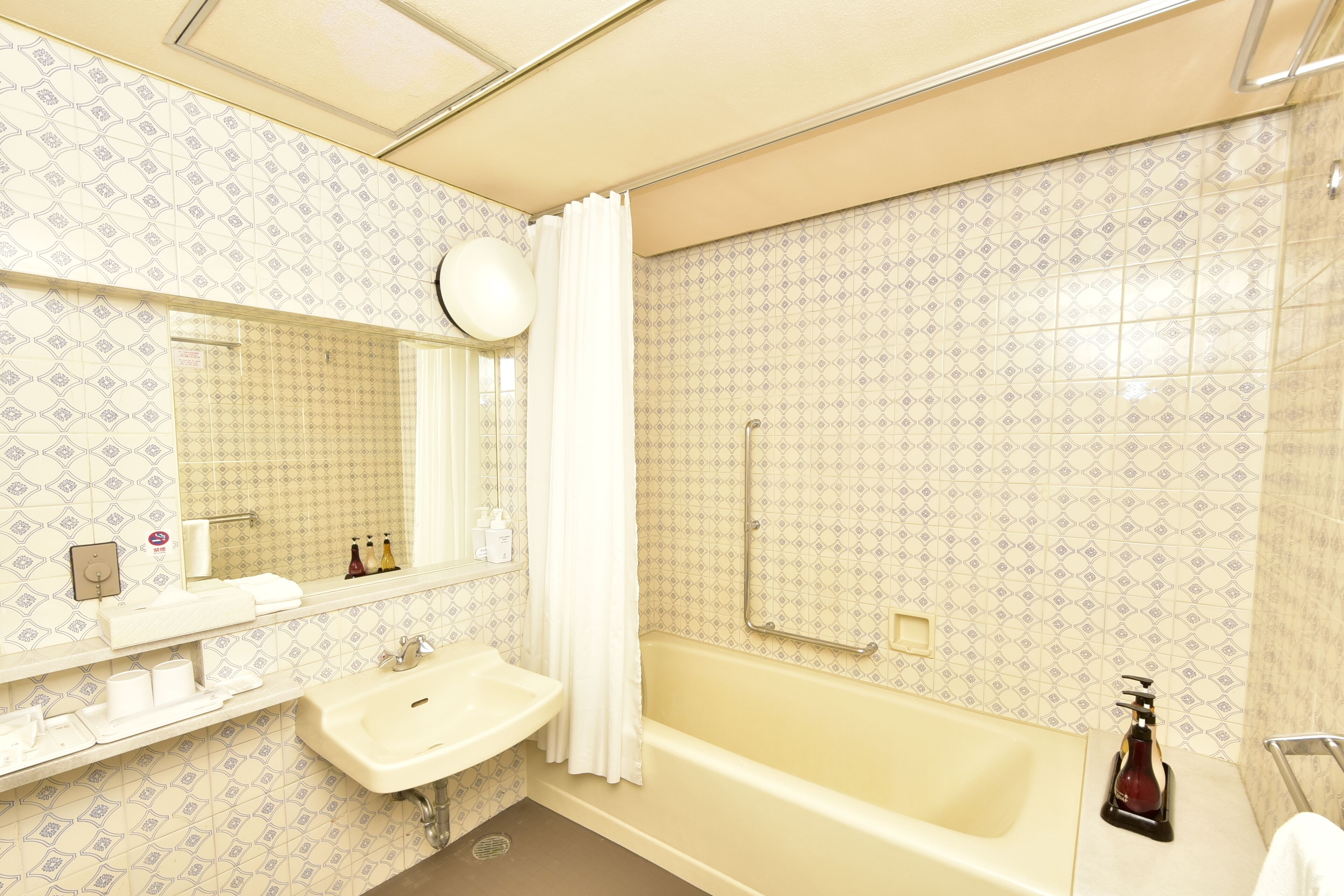 A bathroom with a sink, mirror, and bathtub.