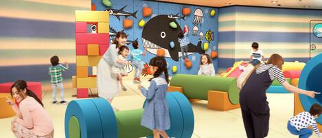 A children's play area with colorful play structures and a mural of sea creatures.