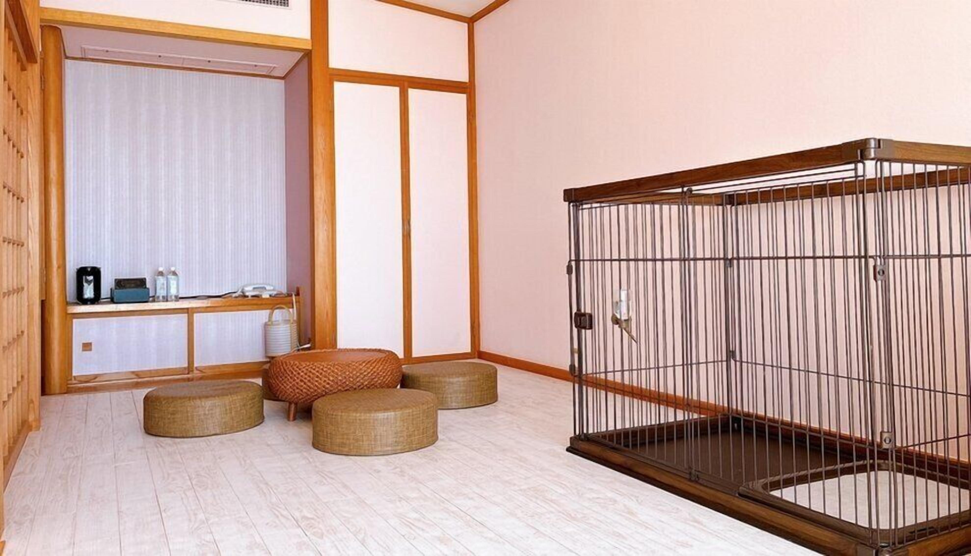 Una habitación con piso de madera, una zona de estar con esteras de tatami, una habitación tradicional japonesa con puerta corredera, y un pequeño gabinete de madera con objetos encima.