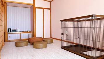 Una habitación con piso de madera, una zona de estar con esteras de tatami, una habitación tradicional japonesa con puerta corredera, y un pequeño gabinete de madera con objetos encima.