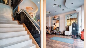 Een modern hotelinterieur met een marmeren trap, houten vloeren en eigentijds meubilair.
