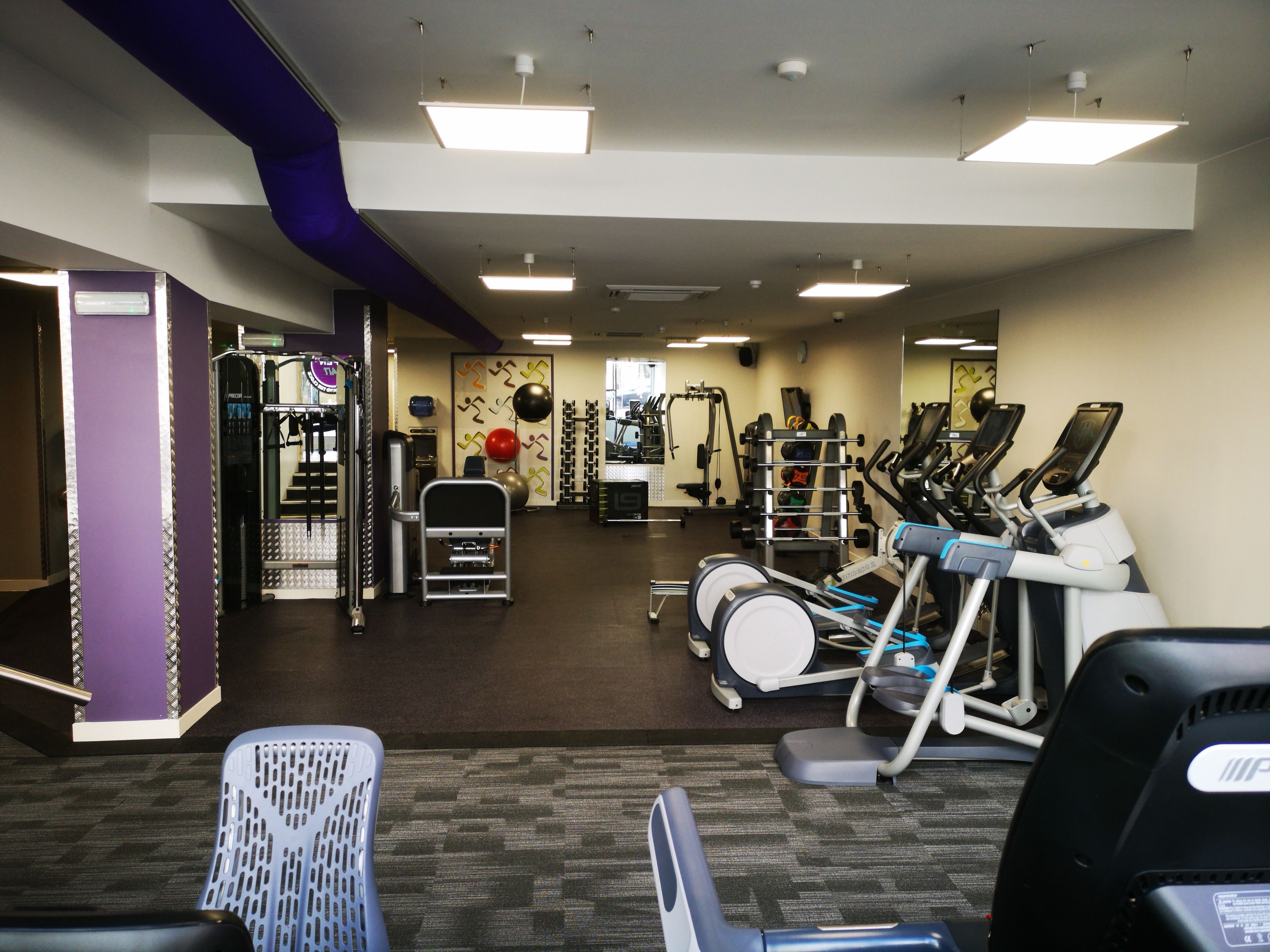 A gym with exercise equipment, a weight rack, and a mirrored wall.