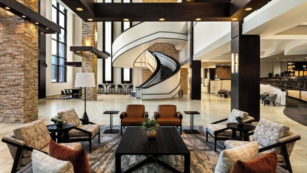 A spacious lobby with a central spiral staircase, comfortable seating areas, and a modern design. - Bloomington-Normal Marriott Hotel & Conference Center (Normal)