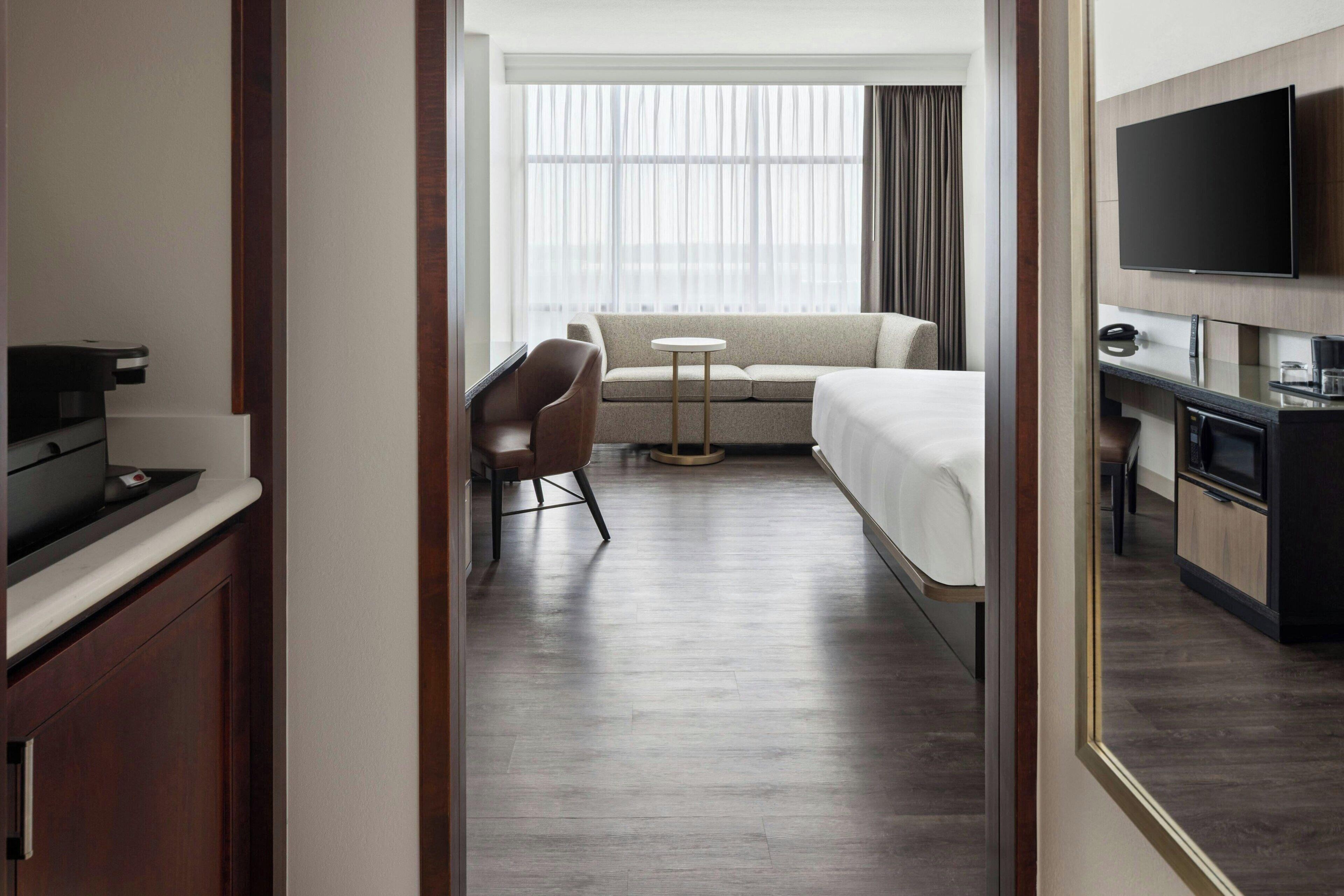 Una habitación de hotel con cama, sofá, televisión, escritorio y silla.