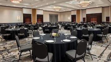 A large conference room with round tables, black tablecloths, and gray chairs.