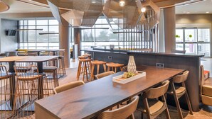 Un restaurante moderno con una mesa común larga, taburetes altos y una zona de bar central.