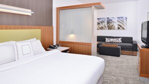 A hotel room with a large bed, a sofa, a TV, and a wooden headboard. - SpringHill Suites by Marriott Ashburn Dulles North (Ashburn)