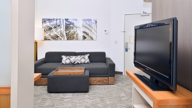 Un salón moderno con un sofá gris, una mesa de centro de madera y un televisor de pantalla plana sobre un mueble de madera.