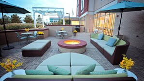 An outdoor patio with seating, a fire pit, and umbrellas. - SpringHill Suites by Marriott Ashburn Dulles North (Ashburn)