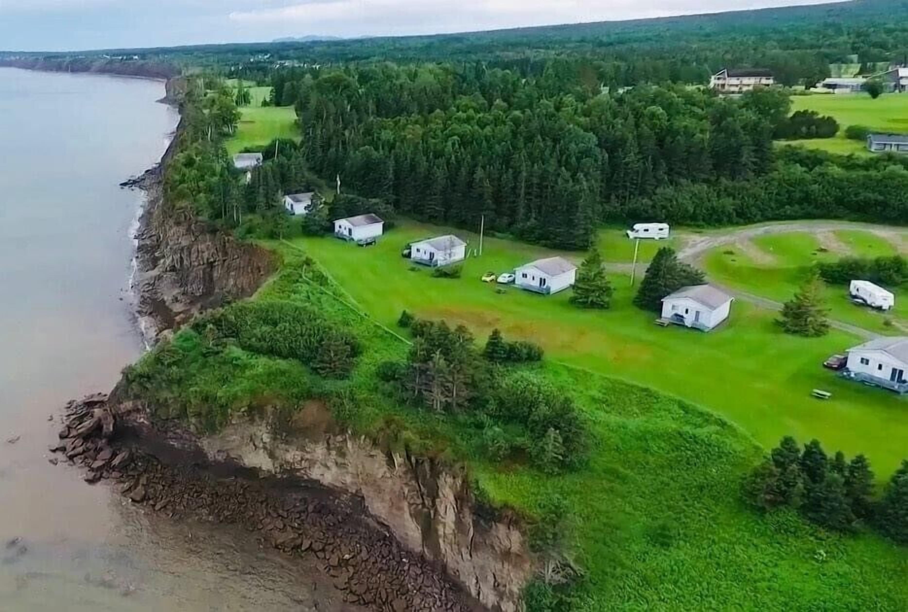 A coastal property with several white buildings, a grassy area, and a rocky shoreline.