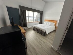 Una habitación de hotel con una cama, un escritorio y una ventana con cortinas.
