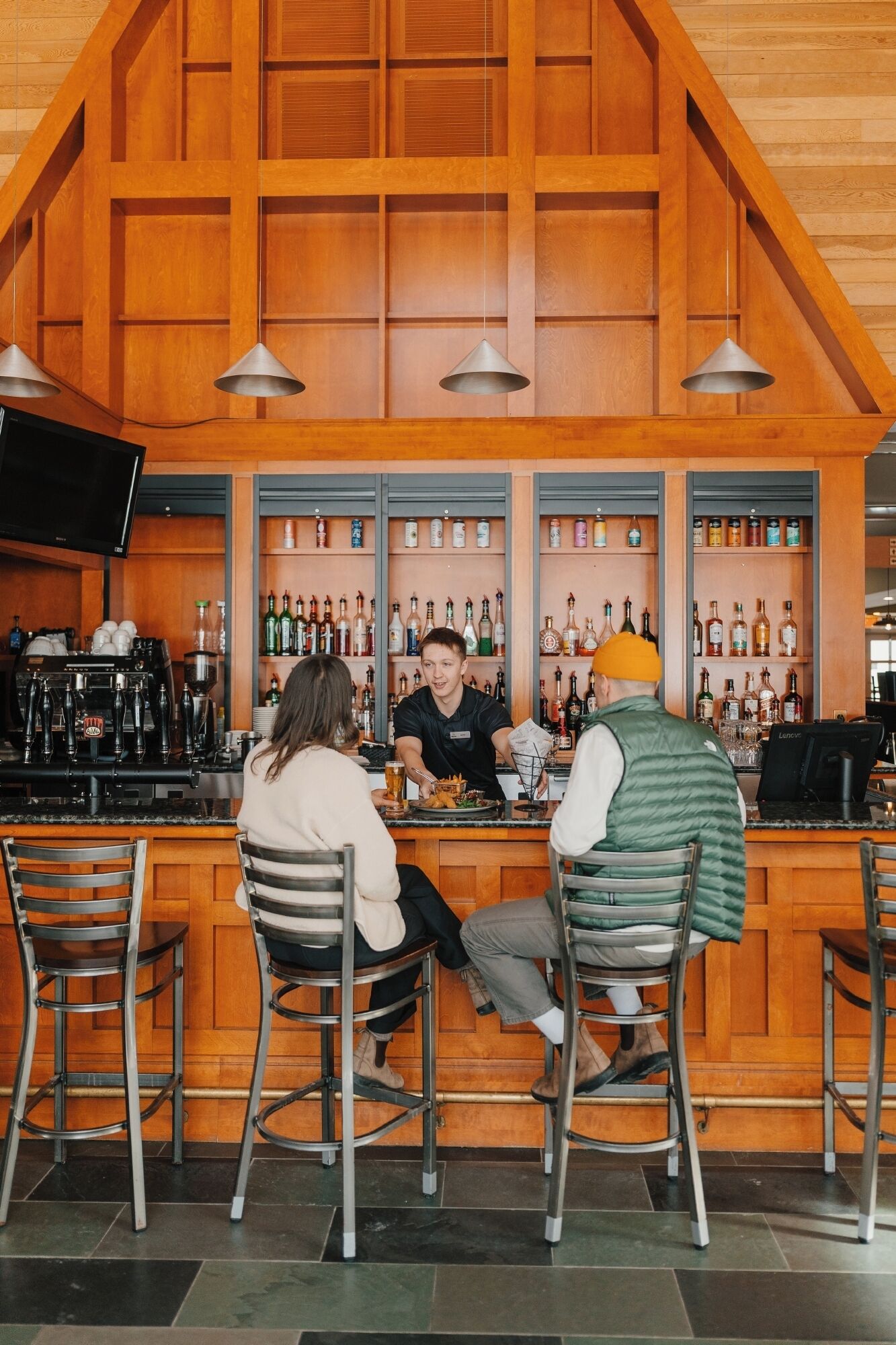 A bar with wooden paneling, a counter, and shelves with bottles.