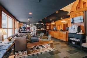 A spacious hotel lobby with a seating area, a reception desk, and a bar. - Gite du Mont-Albert - Sepaq (Mont-Albert)