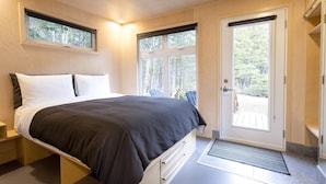 Un dormitorio con cama, una puerta y una ventana.