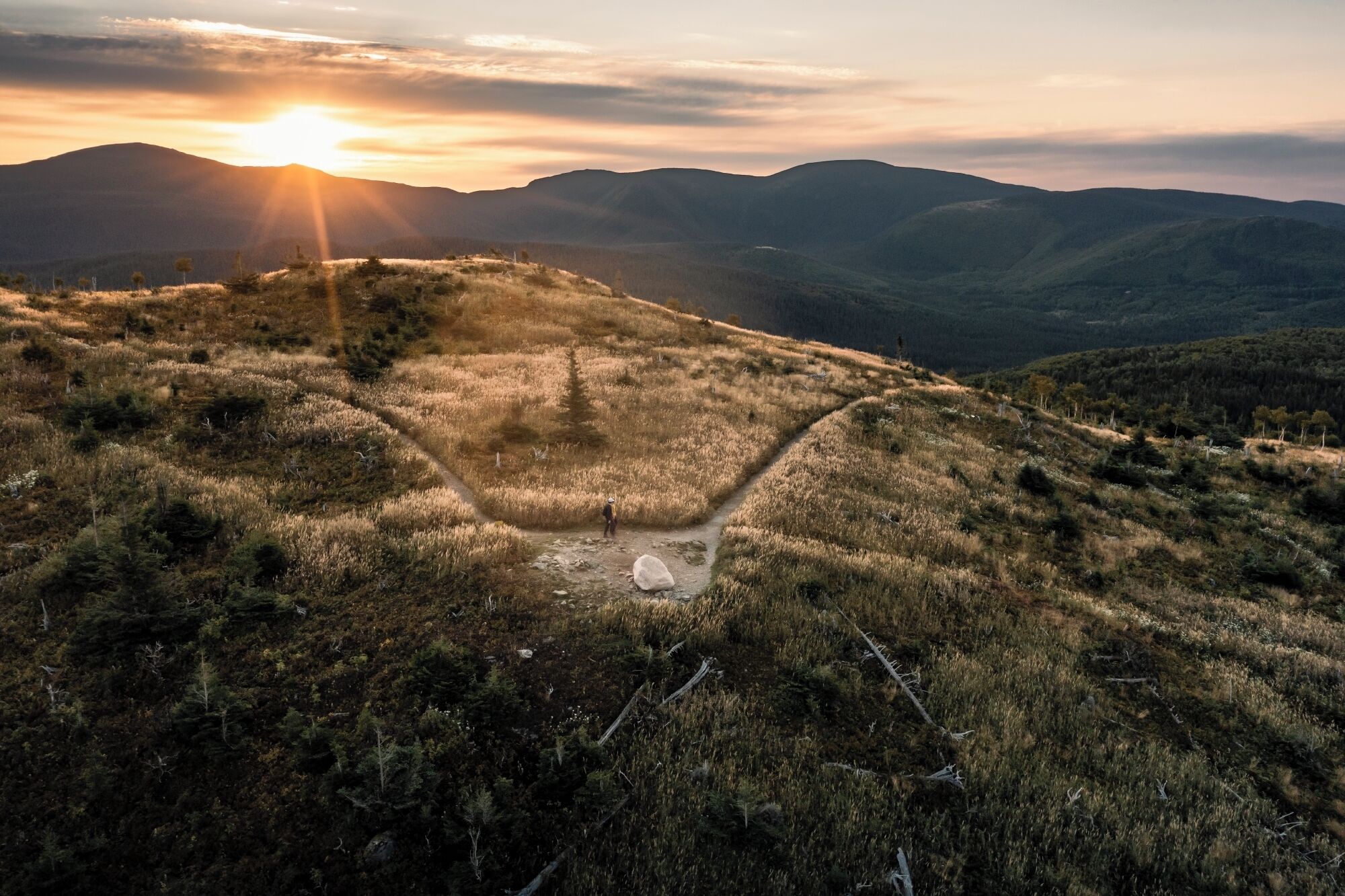 Paisagem acidentada com um caminho que leva a um pequeno espaço aberto.