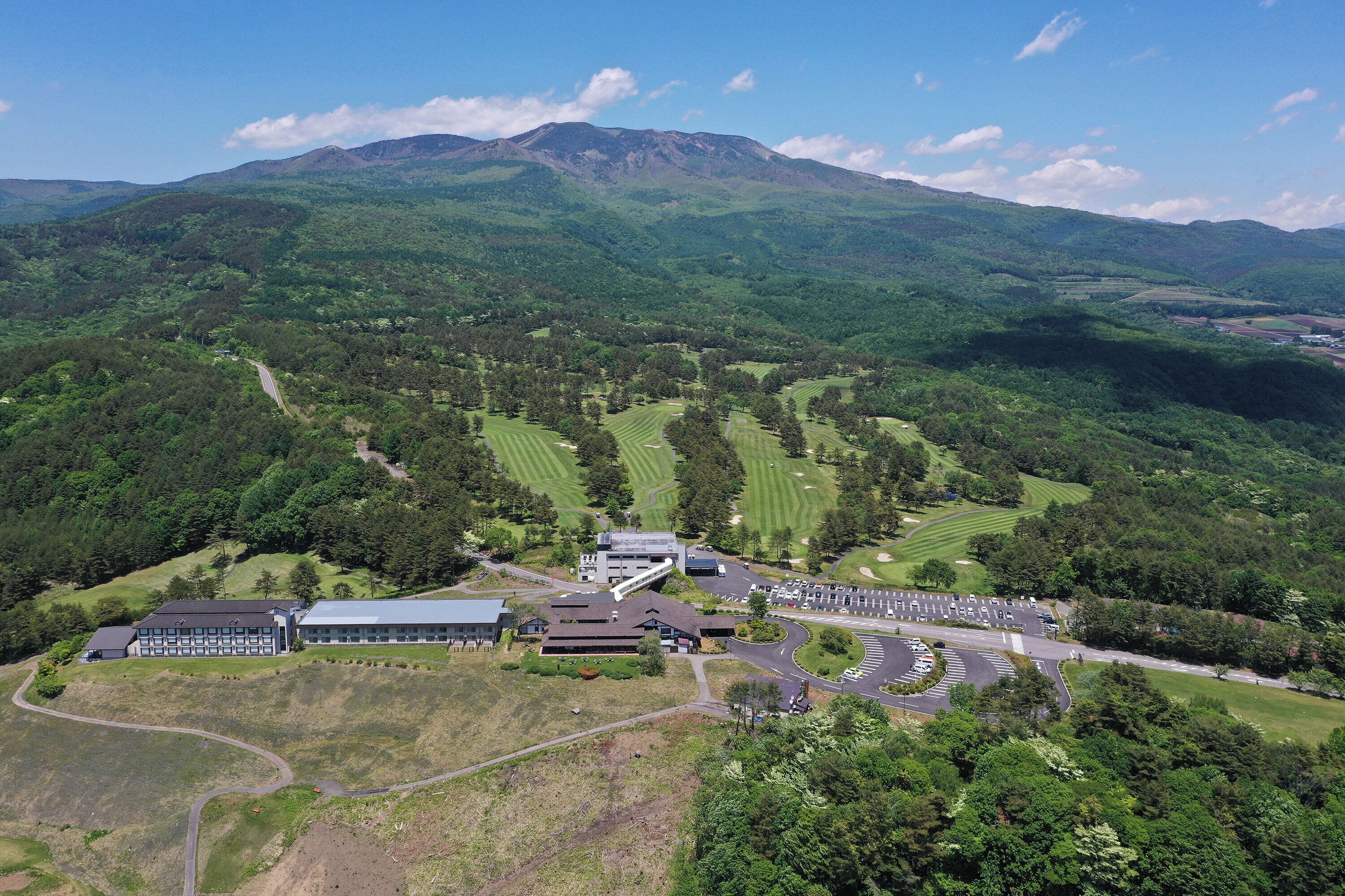 An aerial view of a golf course with a clubhouse and parking area.