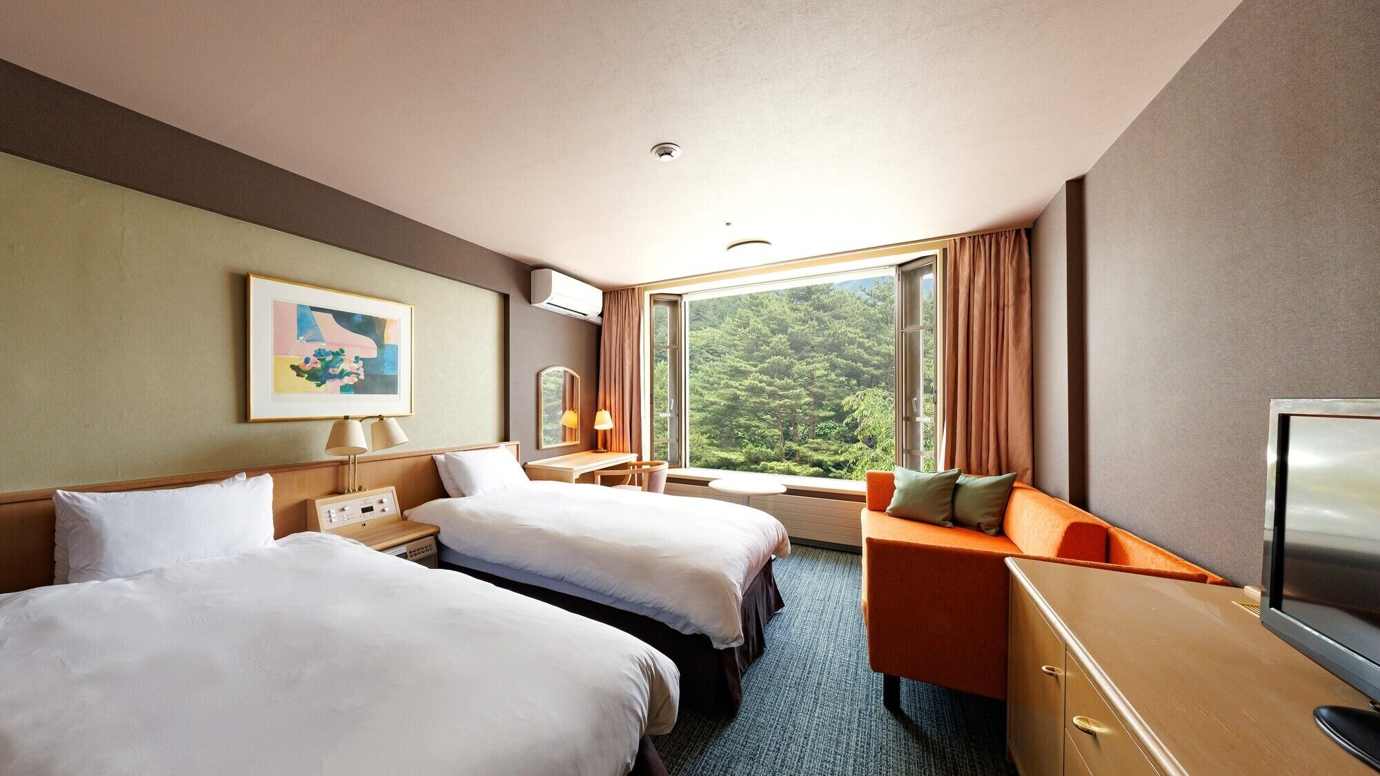 A hotel room with two beds, a desk, a TV, and a window with a forest view.