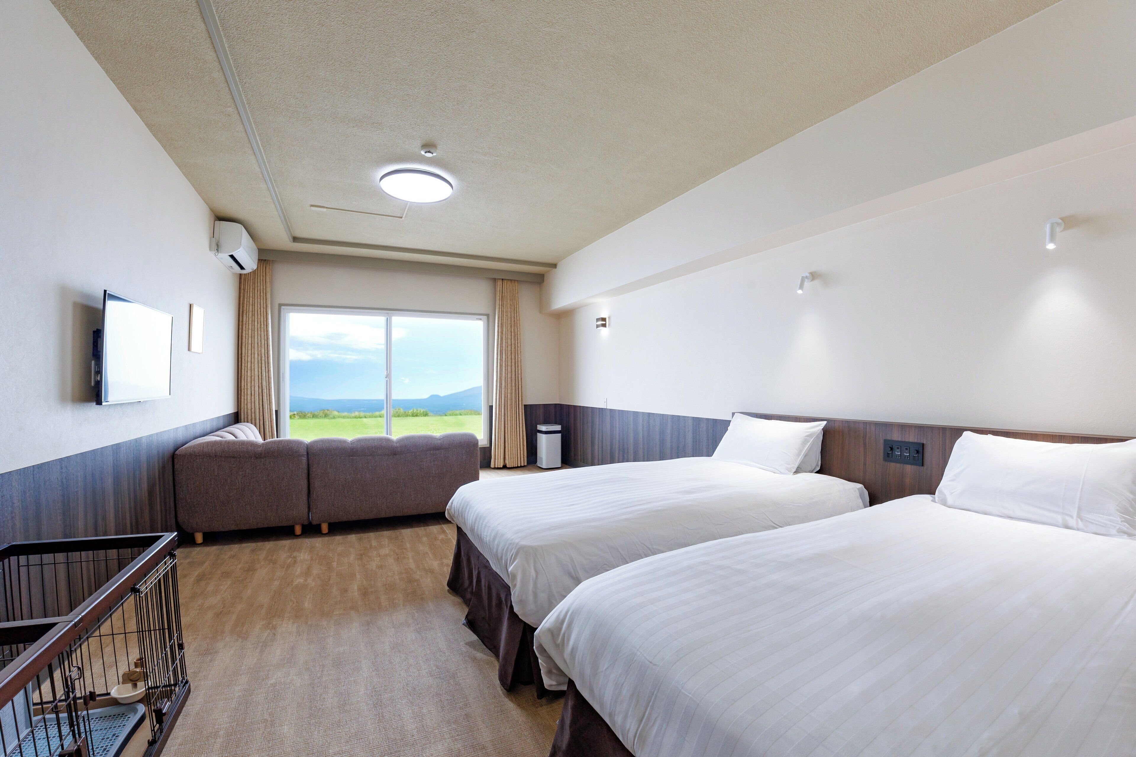 A hotel room with two beds, a TV, a window with a view of the outdoors, and a balcony.
