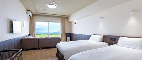 A hotel room with two beds, a TV, a window with a view of the outdoors, and a balcony.