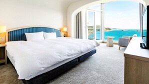 Une chambre d’hôtel avec un grand lit, un bureau et une vue sur la mer.