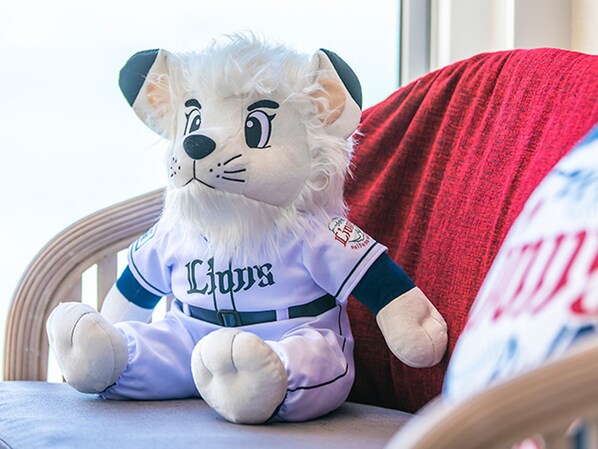 Un peluche con una camiseta que dice 'Lions' sentado en una silla.