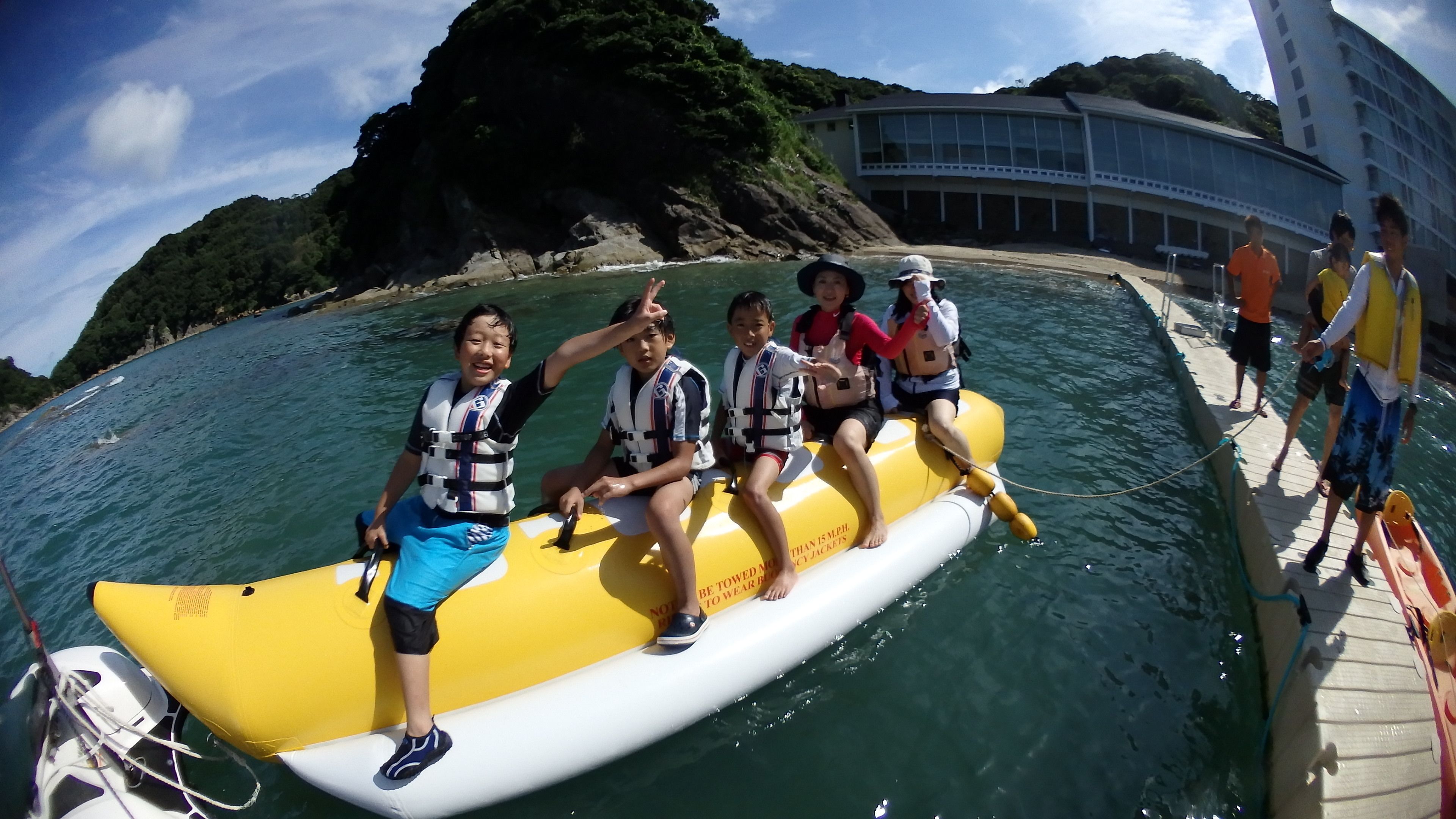A group of people on a yellow raft in a body of water with a building in the background.