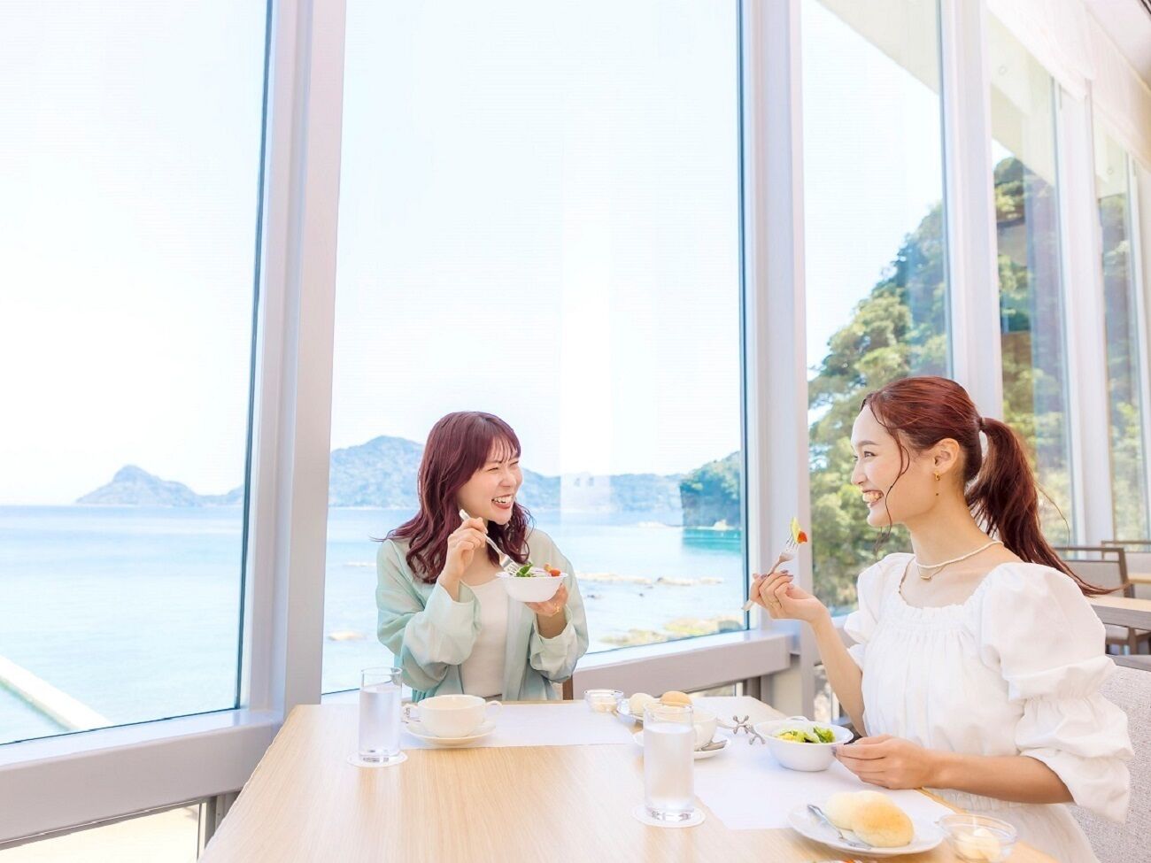 Dos personas cenando en una mesa con vistas al mar y las montañas.