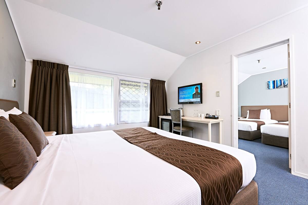 A hotel room with a large bed, a desk, a chair, and a television.