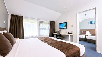 Habitación de hotel con una cama grande, un escritorio, una silla y un televisor.