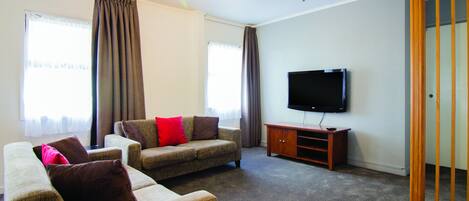 A living room with two sofas, a TV, and a wooden cabinet.
