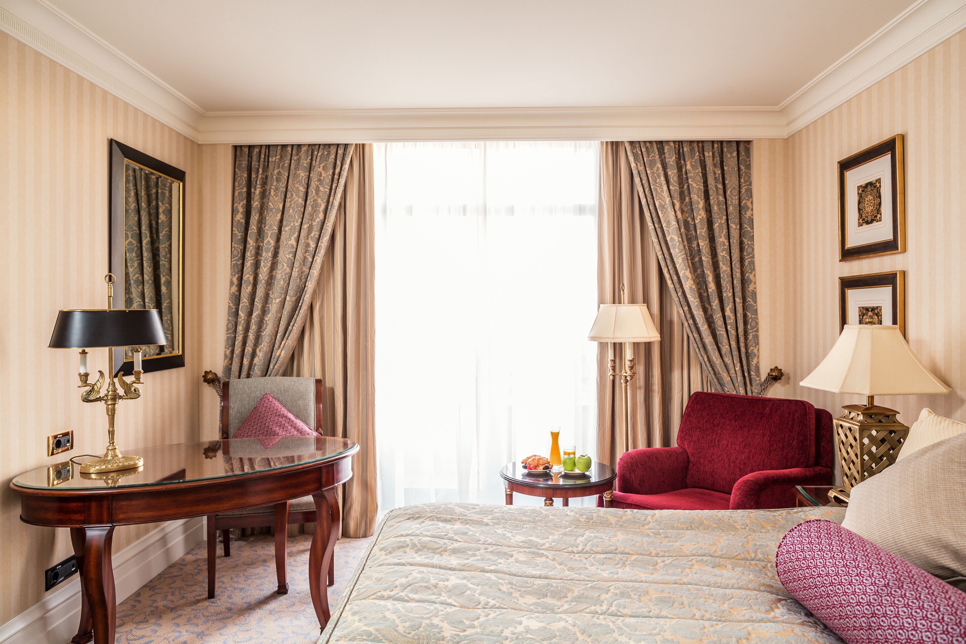 A hotel room with a bed, a desk, a chair, and two lamps.