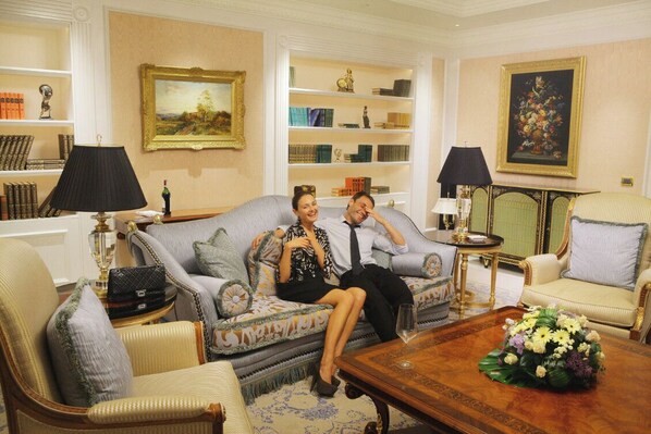 A room with a sofa, armchairs, a coffee table, and a bookshelf.