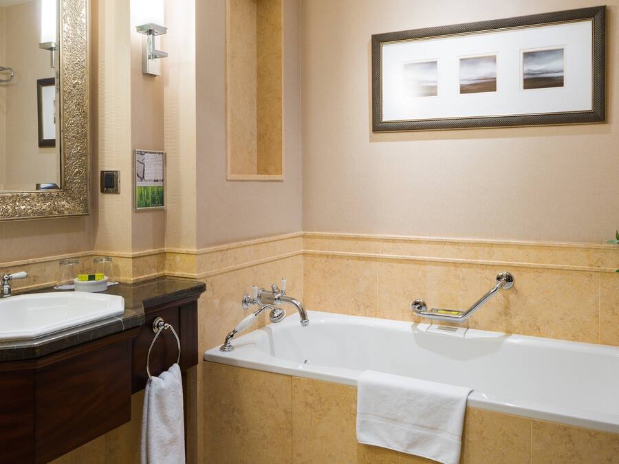 A bathroom with two sinks, a bathtub, and a large mirror.