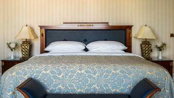 A neatly made bed with a patterned bedspread, two bedside tables with lamps, and a decorative headboard.