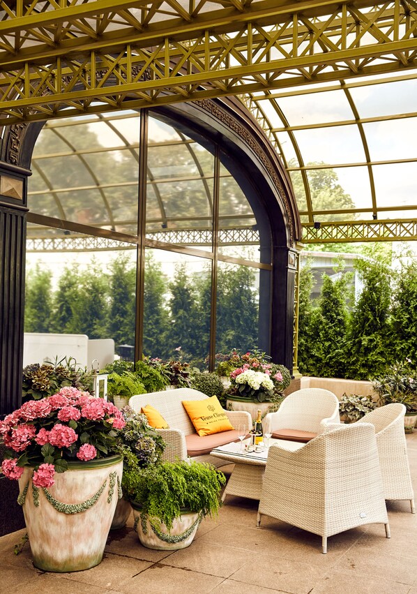 A conservatory with a glass ceiling, wicker furniture, and potted plants. - InterContinental Kyiv by IHG (Kyiv)