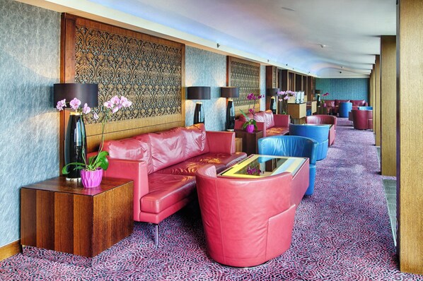 A hotel lobby with a red sofa, blue armchairs, and a patterned carpet.